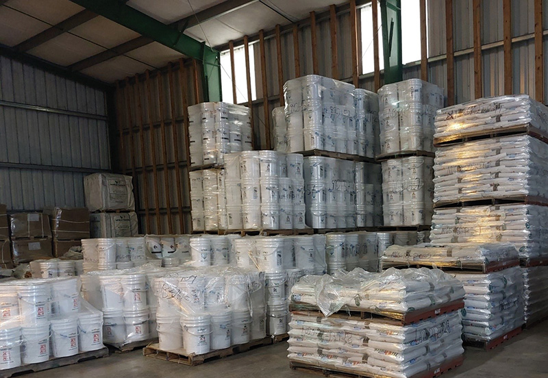 Warehouse with white buckets sitting on pallets wrapped in plastic wrap for shipping