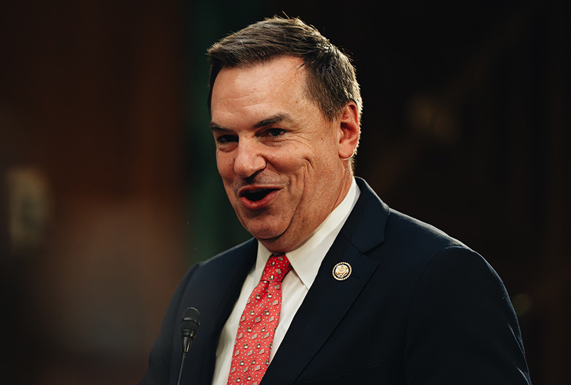 Man in a navy blue suit speaking at a podium