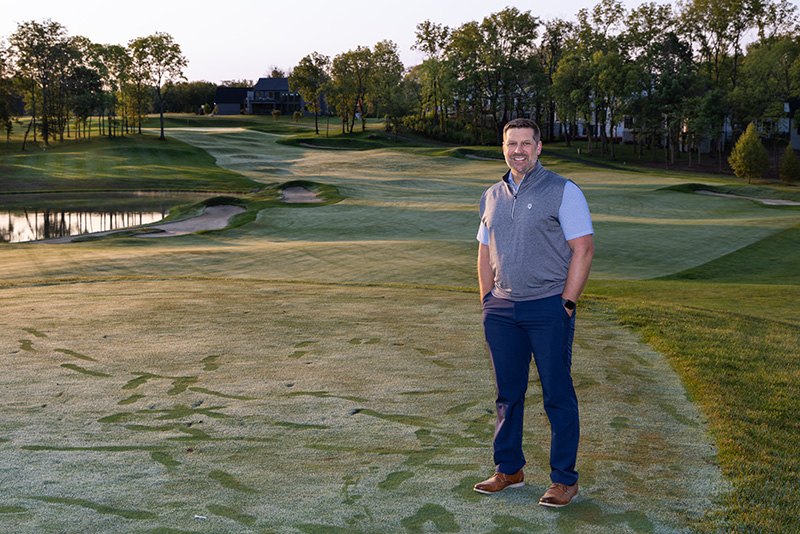 Man standing outside on a golf course at dusk looking at the camera