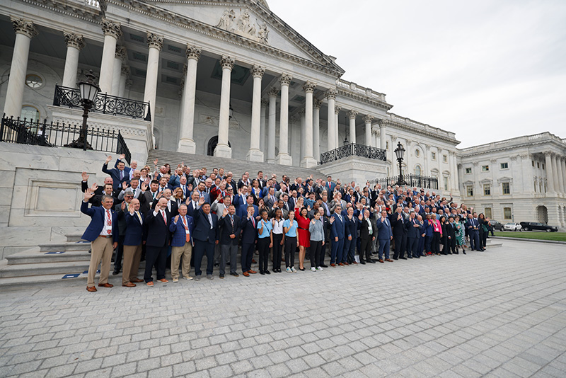 group of people standing outside the United States Capitol Building and waving at the camera