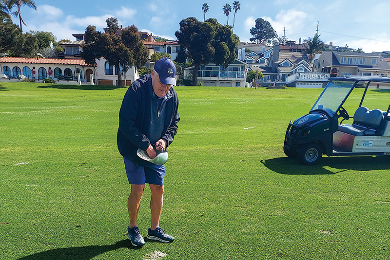 Man fixing a divot on a golf course