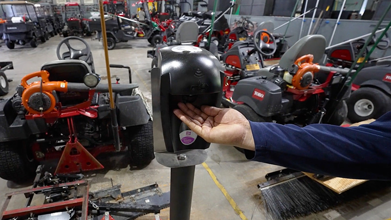 Person inside a golf course shop using hand sanitizer to clean their hands