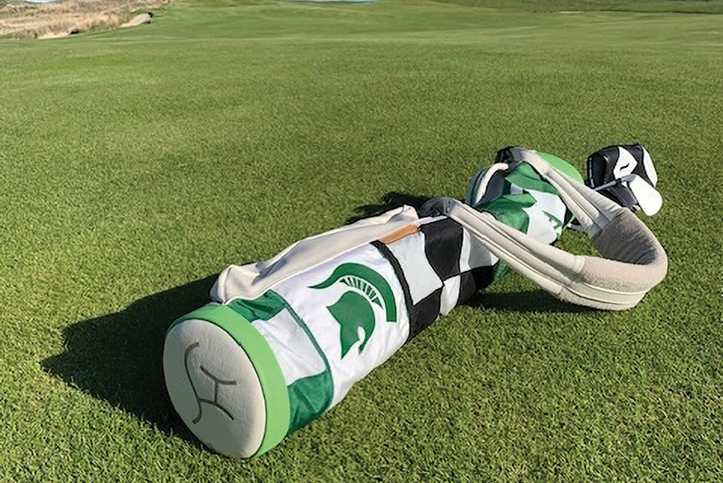 Green and white golf bag lying on a putting green