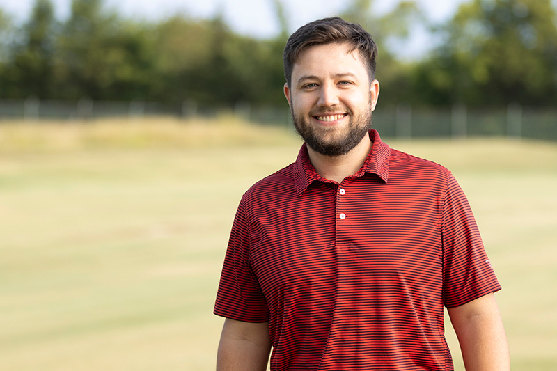 Wendell Hutchens in a red striped polo standing outdoors