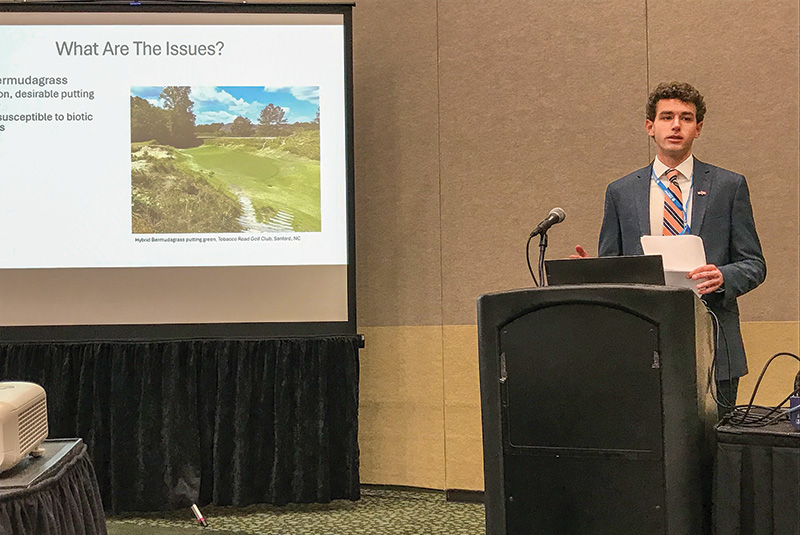 Man in a greenhouse taking care of test plots