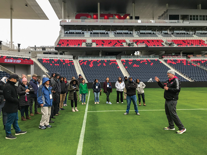 Josh McPherson speaking to a group of turf scientists on the field at St. Louis' CityPark stadium