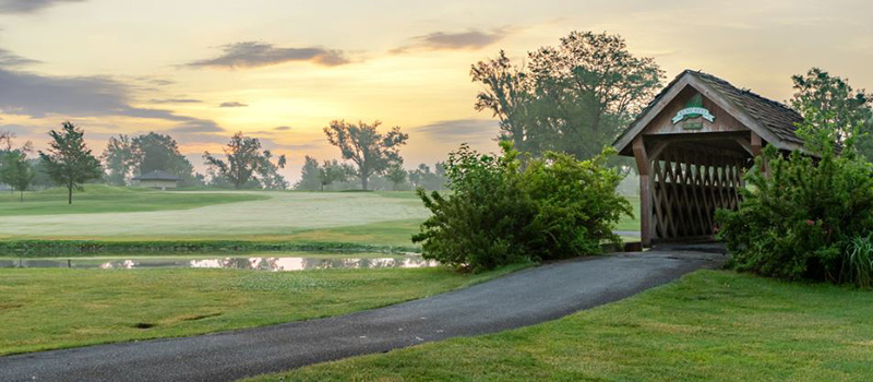 Golf course on a misty early morning with a covered bridge on the right